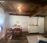 Wohnzimmer in einem Einfamilienhaus mit Holzdecken, weißer Kommode und Vorhängen.