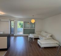 Wohnzimmer in einer 3-Zimmer-Wohnung mit weißem Sofa und Boden in Holzoptik.
