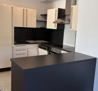Küche in einer 3-Zimmer-Wohnung mit eleganter schwarzer Arbeitsplatte und hellen Schränken.