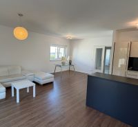 Wohnzimmer in einer 3-Zimmer-Wohnung mit weißem Sofa und Boden in Holzoptik.