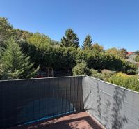 Terrasse einer 3-Zimmer-Wohnung in Wolfsthal mit Blick auf Grünflächen und blauen Himmel.