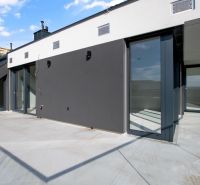 Geräumige Terrasse einer 5- oder mehr Zimmer-Wohnung mit moderner Fassade und Glasgeländer.