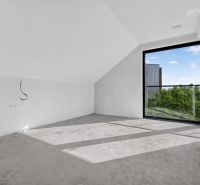 Ein Zimmer mit einem großen Fenster und grauem Boden in einer Mehrzimmerwohnung.