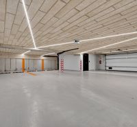 Parkhaus mit Betondecke und -boden, beleuchtet mit linearen Leuchten.