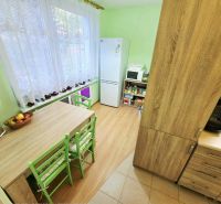 Küche in einer 4-Zimmer-Wohnung mit Tisch, grünen Stühlen und Boden in Holzoptik.