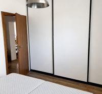 Schlafzimmer in einer 3-Zimmer-Wohnung mit Lampe, Kleiderschrank und Holzboden.