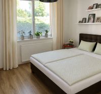 Schlafzimmer mit Holzboden, großem Fenster und einfachem Bett in einer 3-Zimmer-Wohnung.