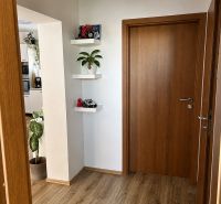 Flur in einer 3-Zimmer-Wohnung mit Türen und Boden in Holzdekor.