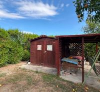 Ein hölzerner Pavillon und eine Schaukel im Garten in Komárno mit Obstbäumen.