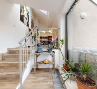 Treppe in einer 4-Zimmer-Wohnung mit dekorativer Skulptur, großem Fenster und Pflanzen in Töpfen.