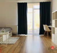 Einzimmerwohnung mit Holzboden, Bett, Tisch und weißen Möbeln.