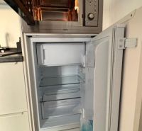 Küchenzeile mit Mikrowelle und offenem Kühlschrank. Boden mit Holzdekor.