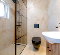 Ein Badezimmer in einem Einfamilienhaus mit einer modernen Duschkabine und einer schwarzen Toilette.