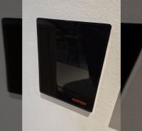 Schwarzes Harvia-Display an der Wand im Inneren der Villa mit Auszeichnungen des Immobilienbüros.
