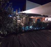 Nachtgarten der Villa in Nine mit Pool und Boden in Holzoptik.