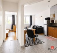 Innenraum einer 2-Zimmer-Wohnung mit Küche, Esstisch und Boden mit Holzdekor.