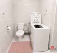 Badezimmer in einer 2-Zimmer-Wohnung mit Waschmaschine und WC auf Fliesen.