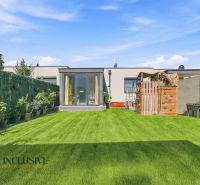 Der Garten des Einfamilienhauses in Oľdza mit Rasen, Kinderspielplatz und Pflanzen in Blumentöpfen.