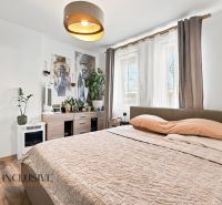 Schlafzimmer mit hellen Wänden, Bett und Dekorationen, Boden mit Holzdekor.