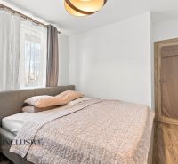 Ein Schlafzimmer in einem Einfamilienhaus mit Holzboden, grauem Bett und Vorhängen.