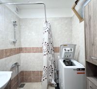 Badezimmer in einer 3-Zimmer-Wohnung mit Waschmaschine, Waschbecken und Duschkabine mit Vorhang.