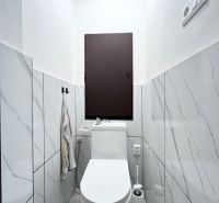 WC in einer 3-Zimmer-Wohnung mit Marmorverkleidung und weißer Sanitärausstattung.