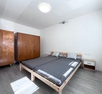 Schlafzimmer mit Bett, Holzschränken und Boden mit Holzdekor in einer 3-Zimmer-Wohnung.