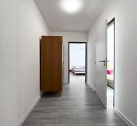 Flur mit Holzboden in einer 3-Zimmer-Wohnung, dunkler Schrank, Türen zu den Zimmern.