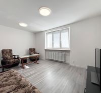 Wohnzimmer in einer 3-Zimmer-Wohnung mit Möbeln, Fernseher und Bodenbelag in Holzoptik.