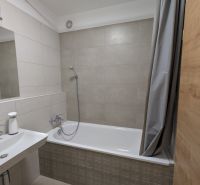 Ein Badezimmer in hellen Tönen mit Badewanne und Duschkabine, ideal für eine 2-Zimmer-Wohnung.