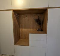 Weißer Einbauschrank mit Holzdekor und Kleiderhaken in einer 2-Zimmer-Wohnung.
