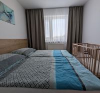 Helles Schlafzimmer mit Bett und Kinderbett in einer 2-Zimmer-Wohnung.