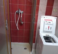 Duschkabine im Badezimmer einer 2-Zimmer-Wohnung, mit einer Waschmaschine platziert.