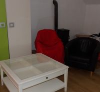 Wohnzimmer in einer Zweizimmerwohnung mit Sesseln und einem Tisch auf einem Boden mit Holzdekor.