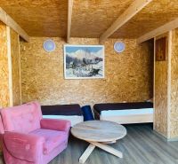 Ein Zimmer in einem Einfamilienhaus mit zwei Betten, einem rosa Sessel und einem Boden in Holzoptik.