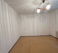 Ein Zimmer in einem Einfamilienhaus mit weißen Wänden und einem Boden in Holzoptik.