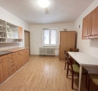 Eine Küche in einem Einfamilienhaus mit einem Boden in Holzoptik, Holzschränken und einem Esstisch.