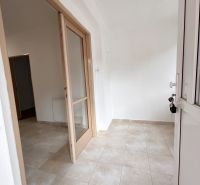 Eingang mit hellen Fliesen und Glastüren in einem Einfamilienhaus.