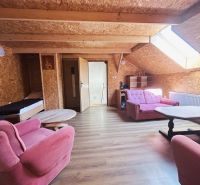 Ein Dachzimmer in einem Einfamilienhaus mit rosa Möbeln und einem Boden in Holzoptik.