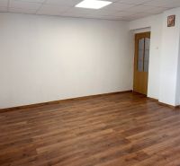 Ein Zimmer in einem Einfamilienhaus mit weißen Wänden und einem Boden in Holzoptik.