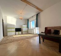 Wohnzimmer in einer Zweizimmerwohnung mit Holzboden und Teppichen.