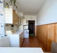 Küche in einer 2-Zimmer-Wohnung mit Holzboden-Dekor und weißen Schränken.