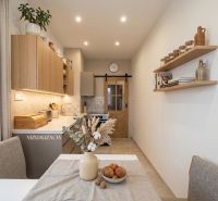 Küche in einer 2-Zimmer-Wohnung mit Holzelementen und Dekorationen auf den Regalen.