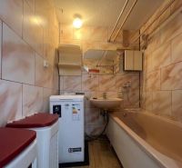 Badezimmer in einer 2-Zimmer-Wohnung mit Badewanne, Waschbecken, Waschmaschine und Fliesen.