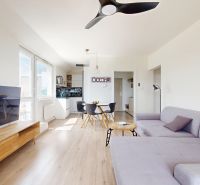 Wohnzimmer in einer 3-Zimmer-Wohnung mit Holzboden, Fernseher und Sitzgelegenheiten.