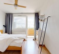 Helles Schlafzimmer mit Bett, Ventilator, Holzboden und Zugang zum Balkon in einer 3-Zimmer-Wohnung.