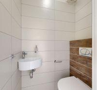 Badezimmer mit Waschbecken, Toilette und einer Wand mit Holzdekor in einer 3-Zimmer-Wohnung.