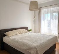 Schlafzimmer in einer 2-Zimmer-Wohnung mit einem bequemen Bett und einem Boden in Holzoptik.