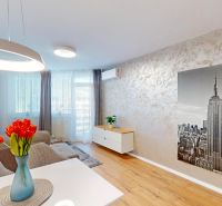 Wohnzimmer mit Holzboden, grauem Sofa und großem Bild eines Wolkenkratzers.