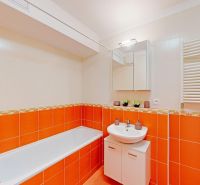 Badezimmer in einer 2-Zimmer-Wohnung mit orange-weißen Fliesen, Badewanne und Waschbecken.
